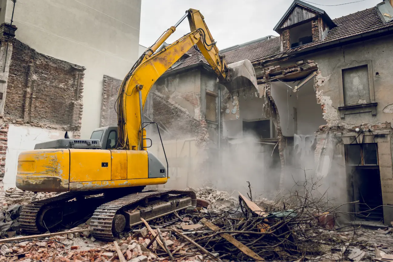 Yellow excavator demolishing a residential structure for RHL Build HB Earthworks.
