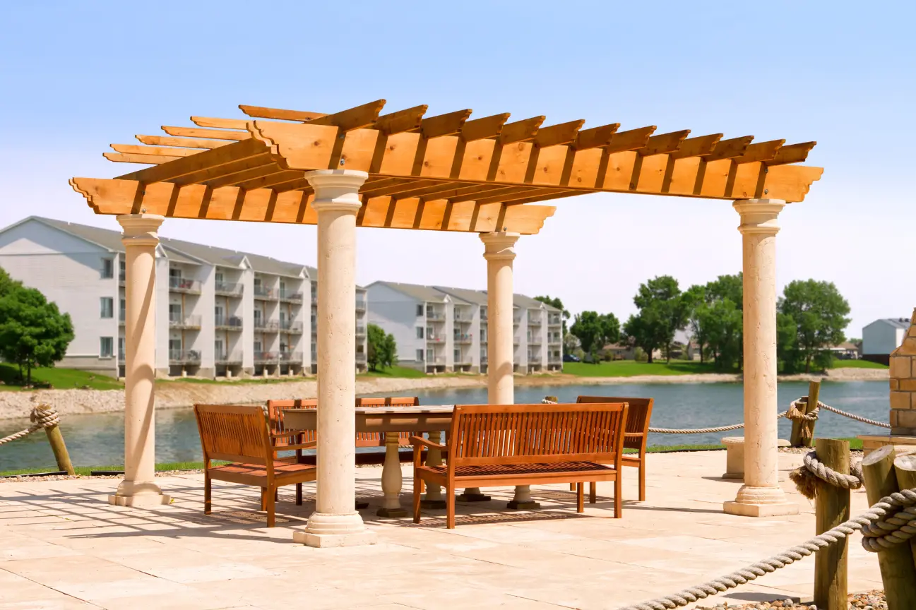 A classic timber pergola with architectural columns built over a paved waterfront patio and dining area by RHL Build HB Pergolas.